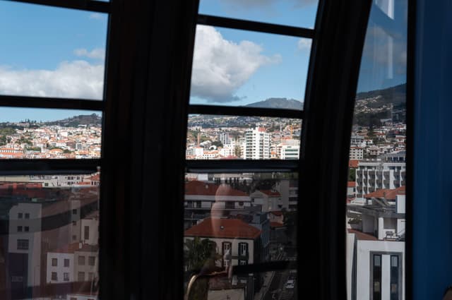 A cityscape seen through large, arched windows with a partially cloudy sky in the background